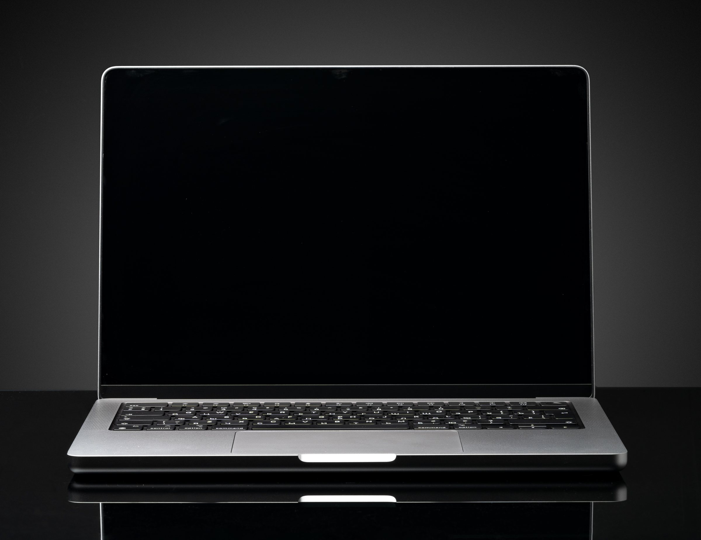 Un MacBook sur un bureau sombre exécutant MiniPrompter. Une bande de lumière chaude
              court le long des bords de l'écran, et un texte défile dans une fenêtre qui monte
              jusqu'au sommet de l'écran et passe derrière l'encoche, avec une fine ligne de
              lecture rouge en travers.